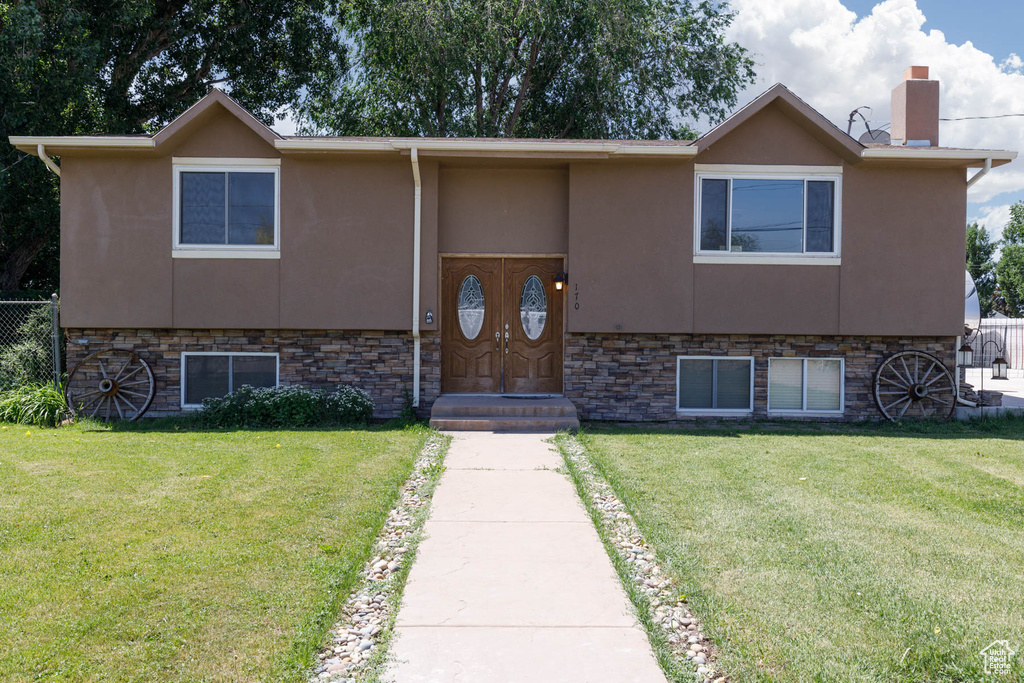 View of front of house with stucco siding, a chimney, and stone siding