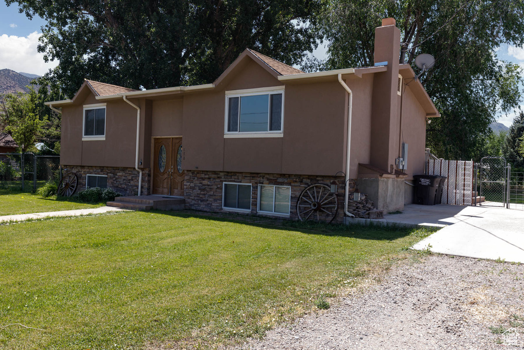View of front of house with a chimney, driveway, stucco siding, a gate, and stone siding