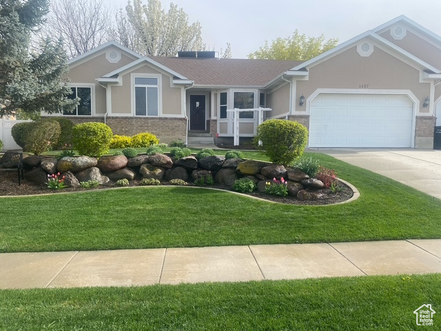 Ranch-style home featuring stucco siding, driveway, a garage, and a front lawn