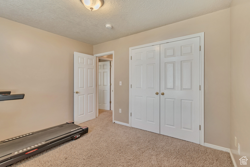 Workout room featuring carpet flooring, baseboards, and a textured ceiling