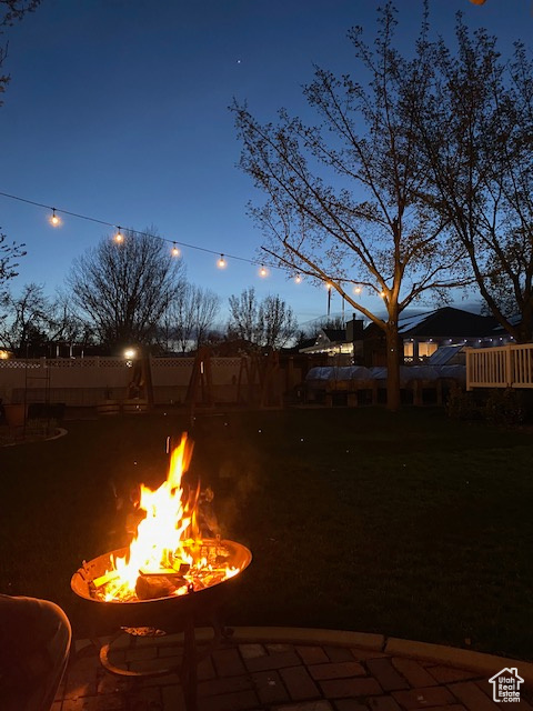 View of yard with an outdoor fire pit and fence