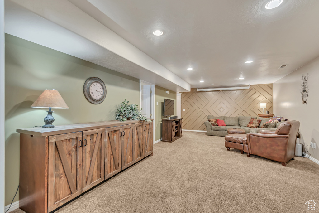 Living room with an accent wall, wood walls, baseboards, light colored carpet, and recessed lighting