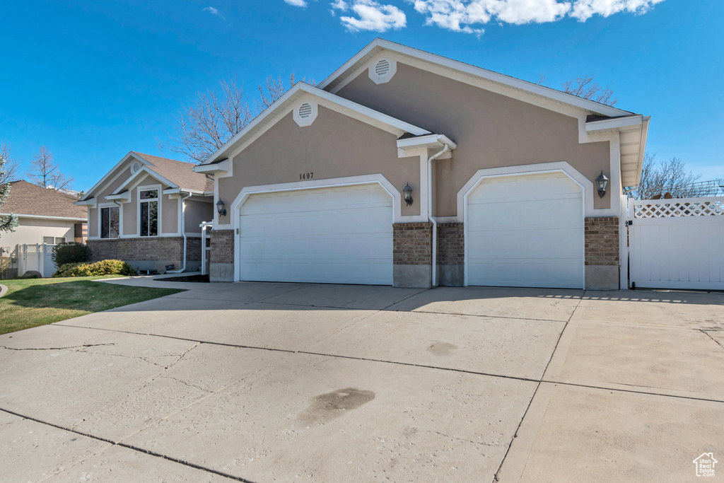 View of front facade featuring driveway, a garage, fence, and stucco siding