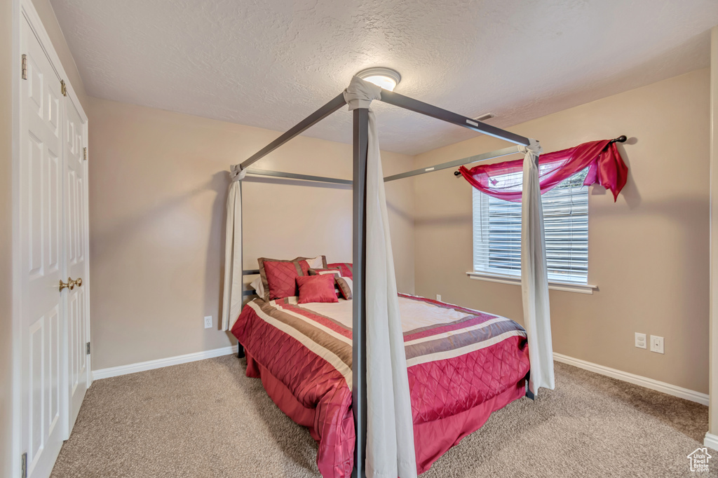 Bedroom featuring baseboards, a textured ceiling, and carpet