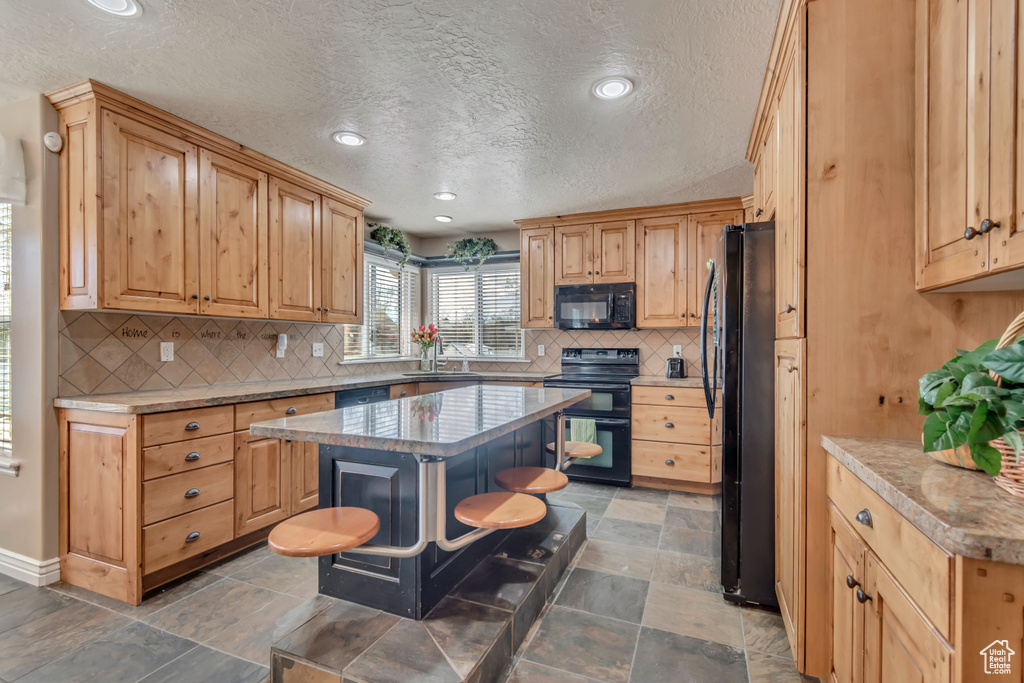 Kitchen featuring recessed lighting, a center island, backsplash, a sink, and black appliances