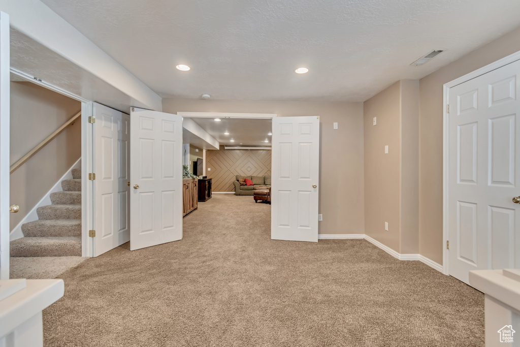 Finished basement with stairs, recessed lighting, baseboards, visible vents, and light carpet
