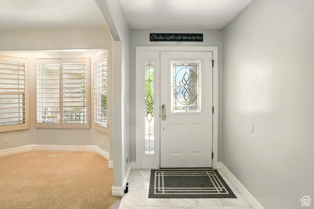Carpeted entrance foyer featuring arched walkways and baseboards