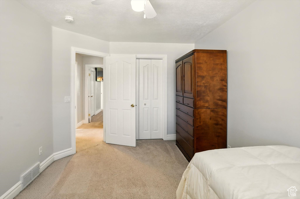 Bedroom with light colored carpet, a closet, and ceiling fan