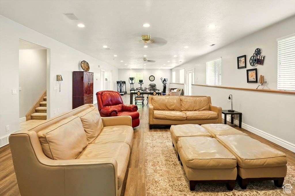 Living room featuring wood finished floors, ceiling fan, recessed lighting, and stairway