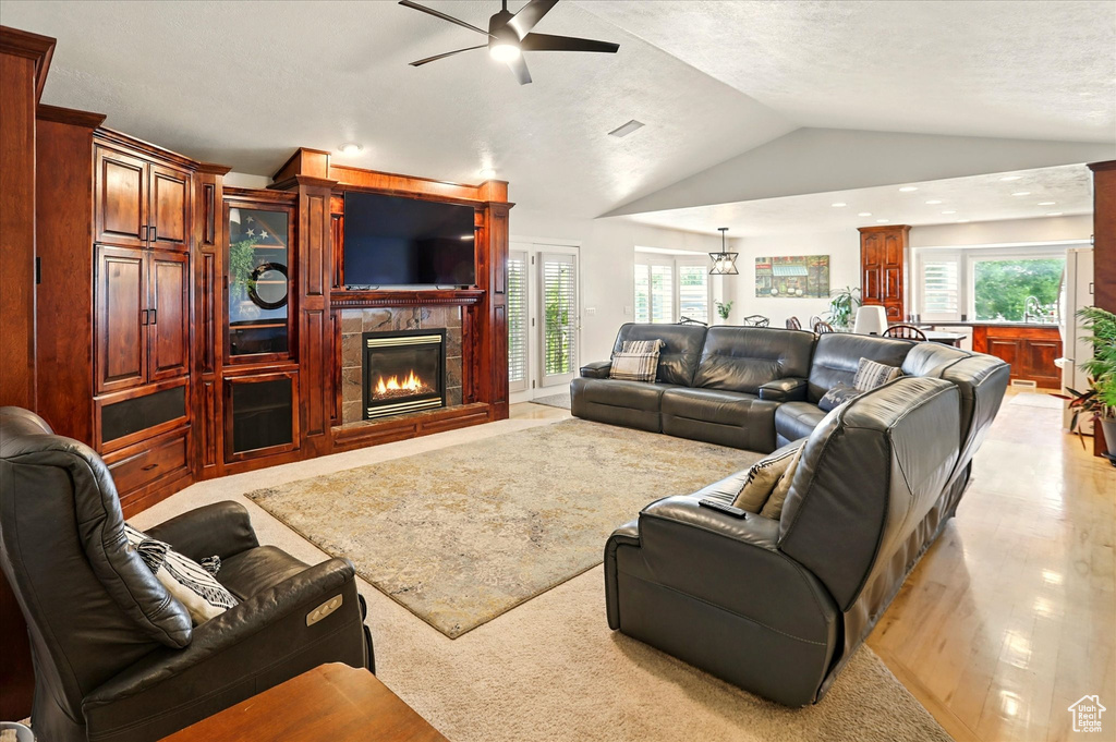 Living room featuring a ceiling fan, lofted ceiling, a fireplace, plenty of natural light, and recessed lighting