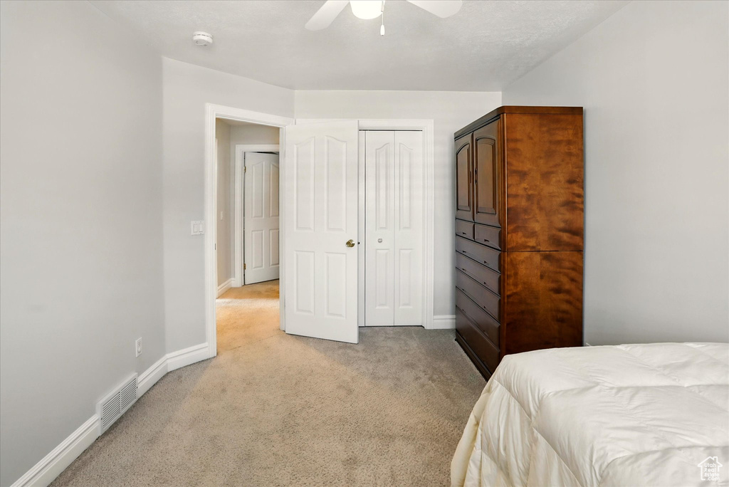 Bedroom with light carpet, a closet, and a ceiling fan