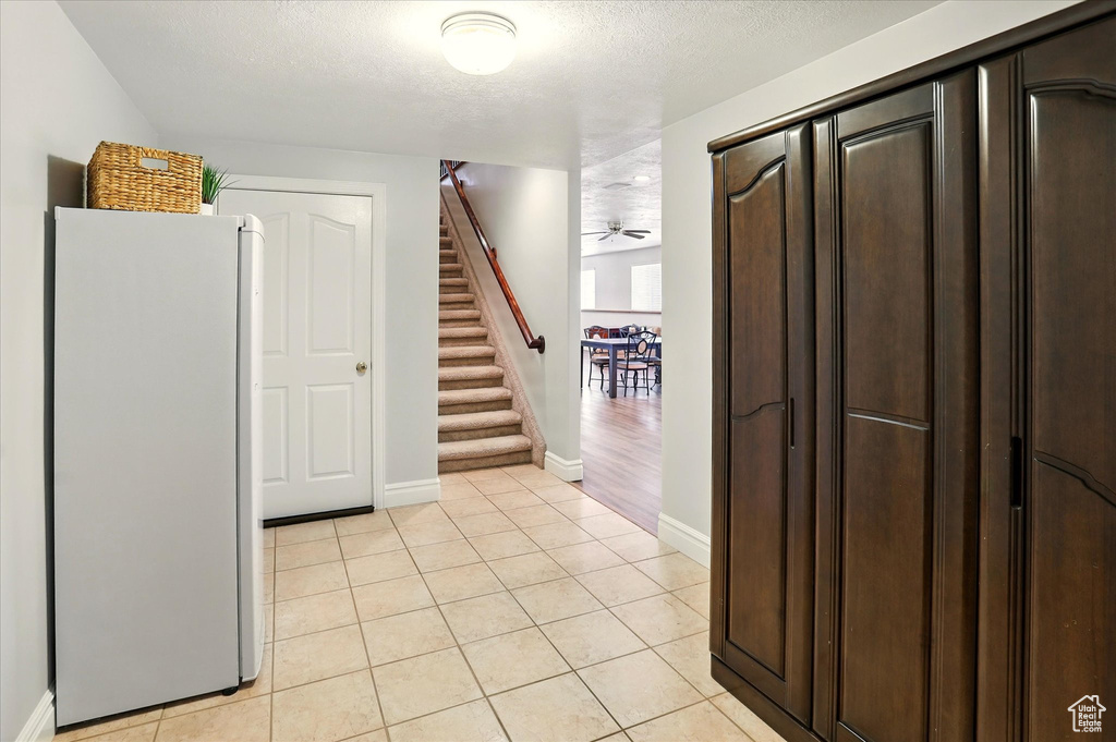 Interior space featuring stairs, light tile patterned floors, and a textured ceiling