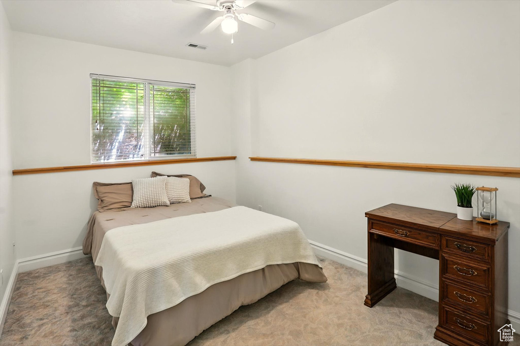 Bedroom with light colored carpet and a ceiling fan
