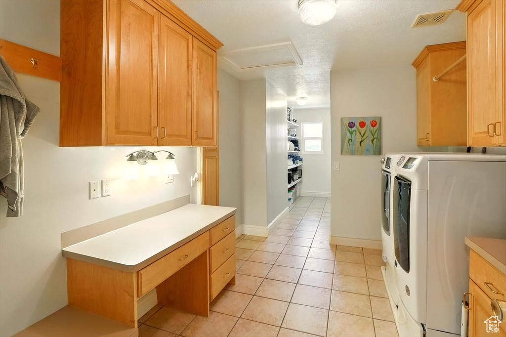 Washroom featuring separate washer and dryer, cabinet space, attic access, and light tile patterned flooring