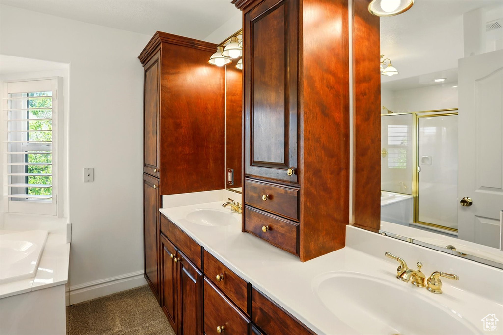 Bathroom with double vanity, a shower with shower door, and a tub to relax in