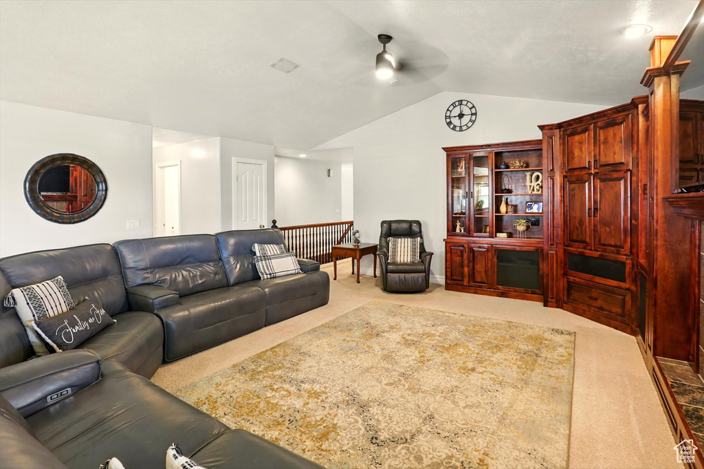 Living area featuring a ceiling fan, carpet flooring, and vaulted ceiling