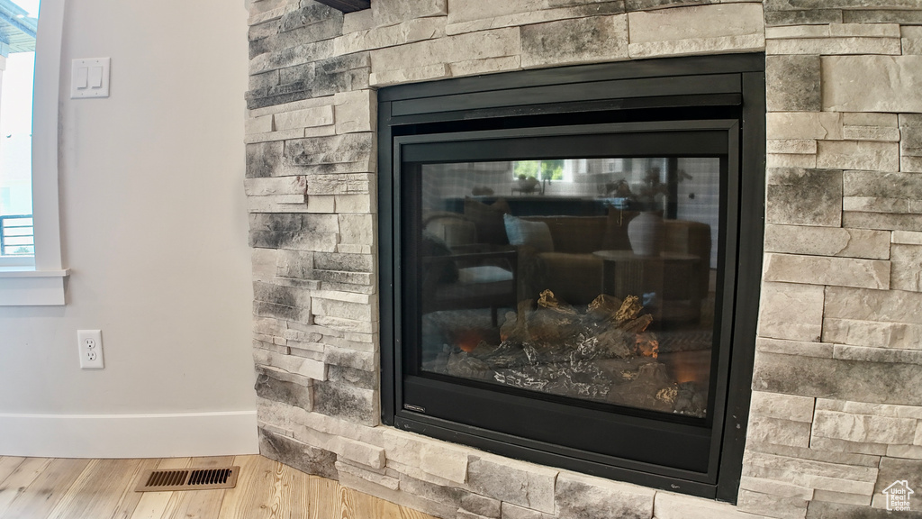 Detailed view of wood finished floors, baseboards, and a stone fireplace