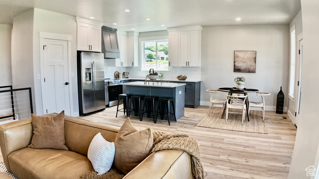 Kitchen featuring stainless steel appliances, a kitchen bar, light wood-type flooring, open floor plan, and a center island