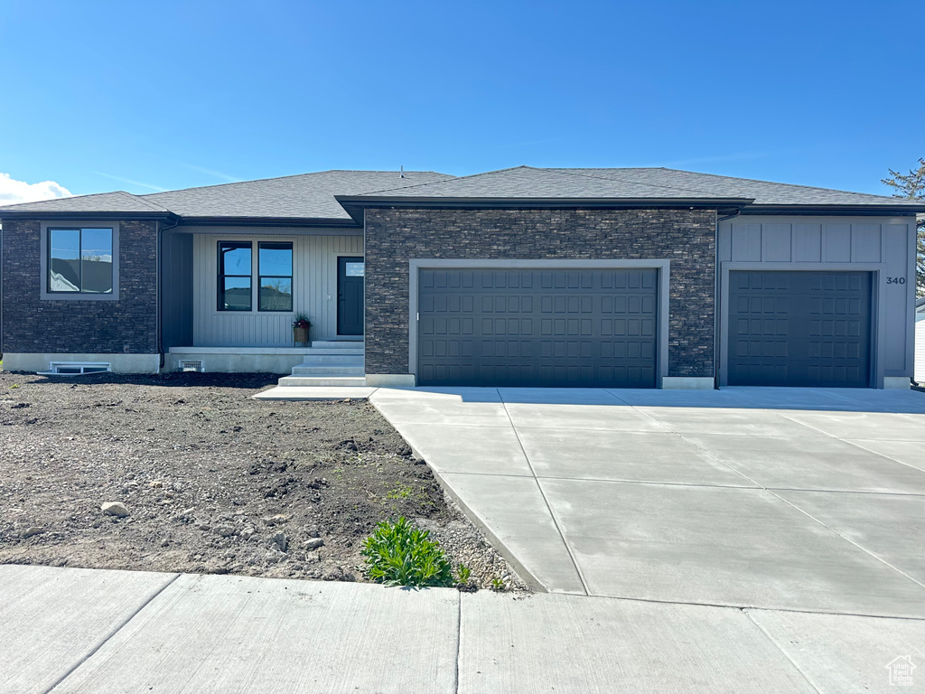Prairie-style home with a garage, a shingled roof, and concrete driveway