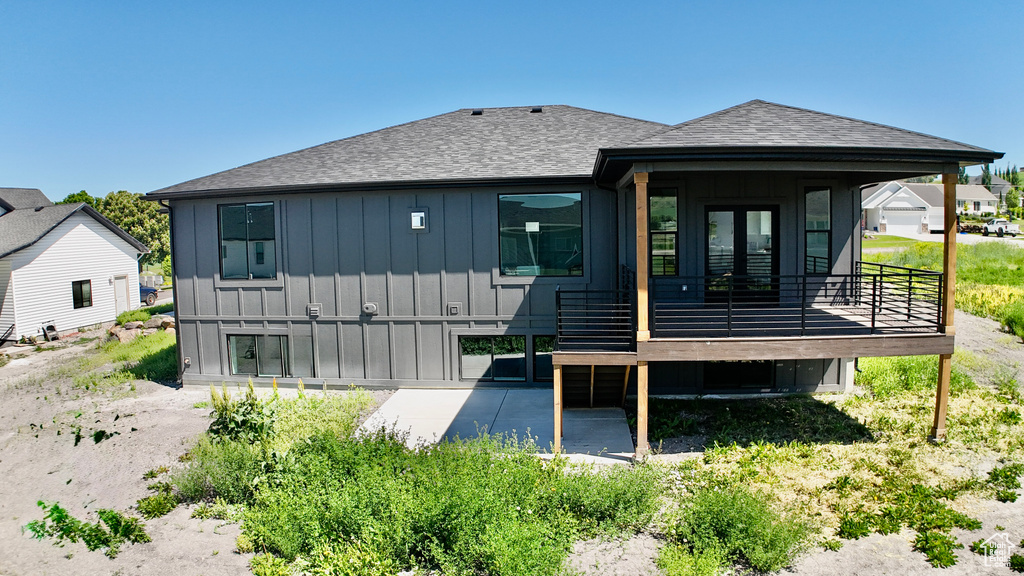 Back of property with board and batten siding and roof with shingles