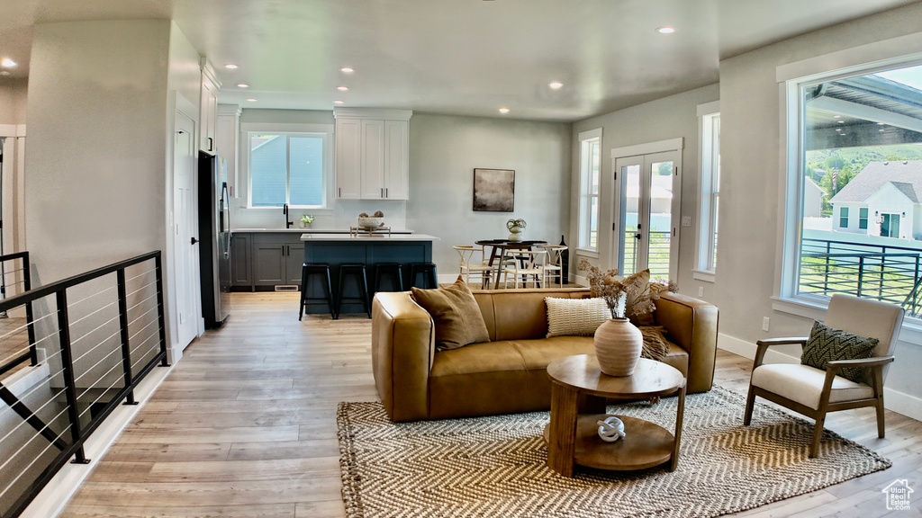 Living area featuring healthy amount of natural light, light wood-type flooring, recessed lighting, french doors, and baseboards