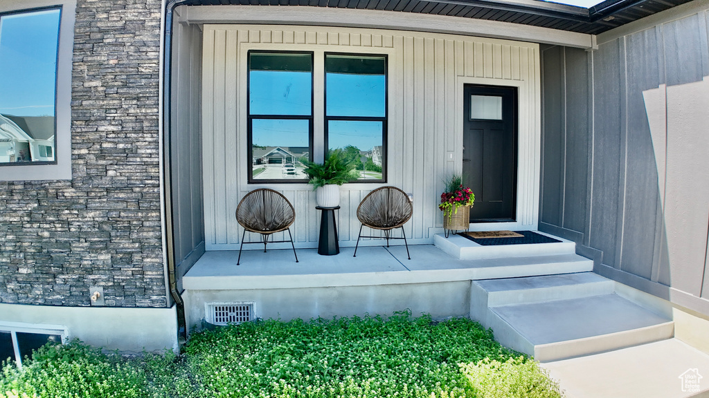 View of exterior entry featuring stone siding and covered porch