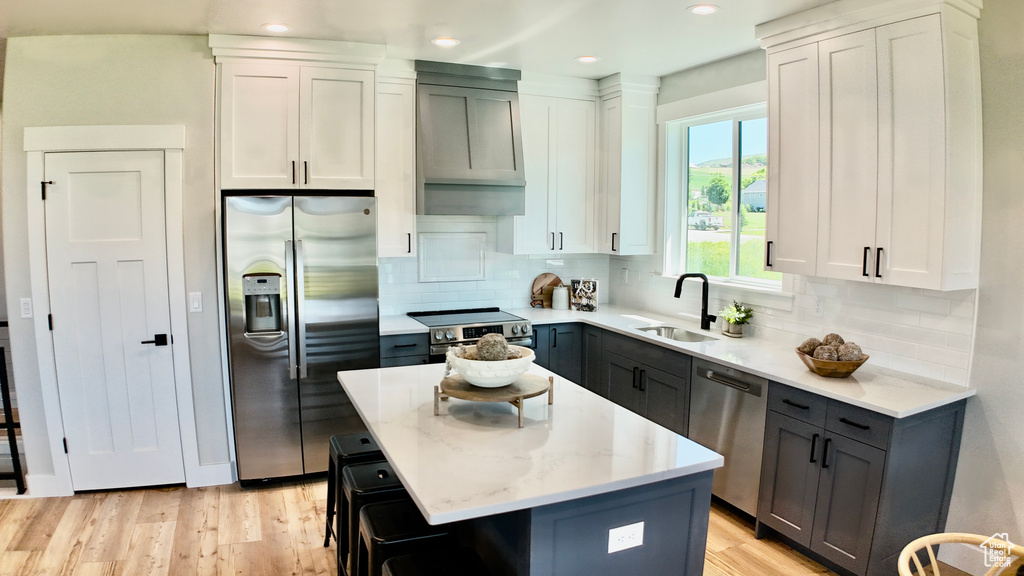 Kitchen with stainless steel appliances, a sink, light wood-type flooring, decorative backsplash, and recessed lighting