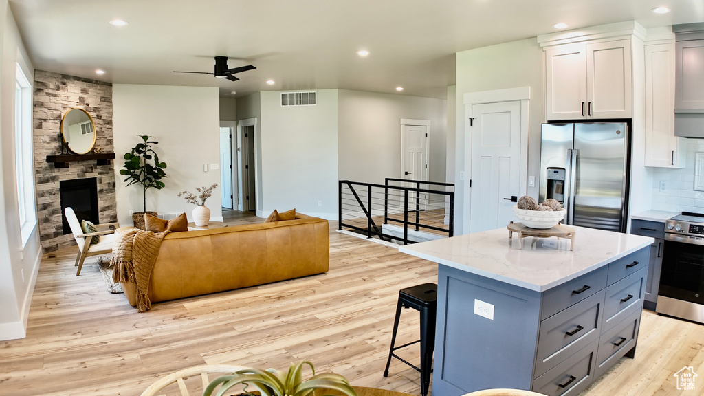 Kitchen featuring appliances with stainless steel finishes, ceiling fan, open floor plan, a center island, and light wood-type flooring