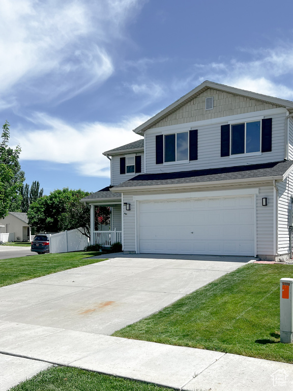 View of front facade with concrete driveway, a front yard, a garage, and covered porch