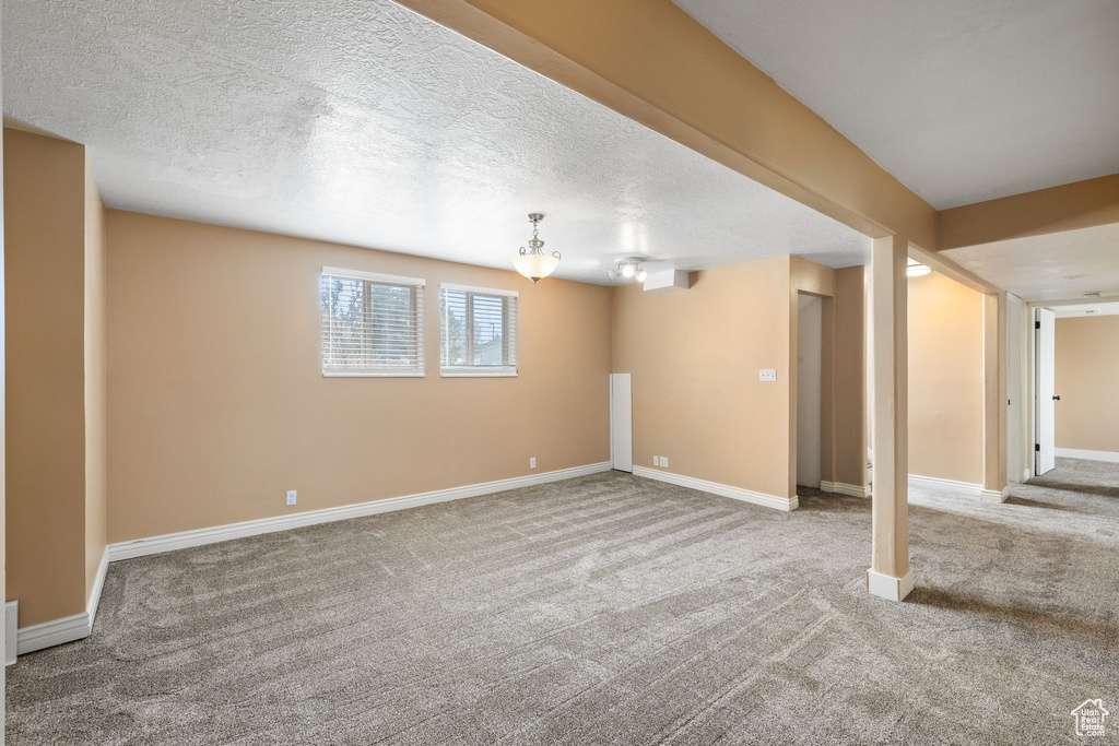 Below grade area with carpet flooring, baseboards, and a textured ceiling