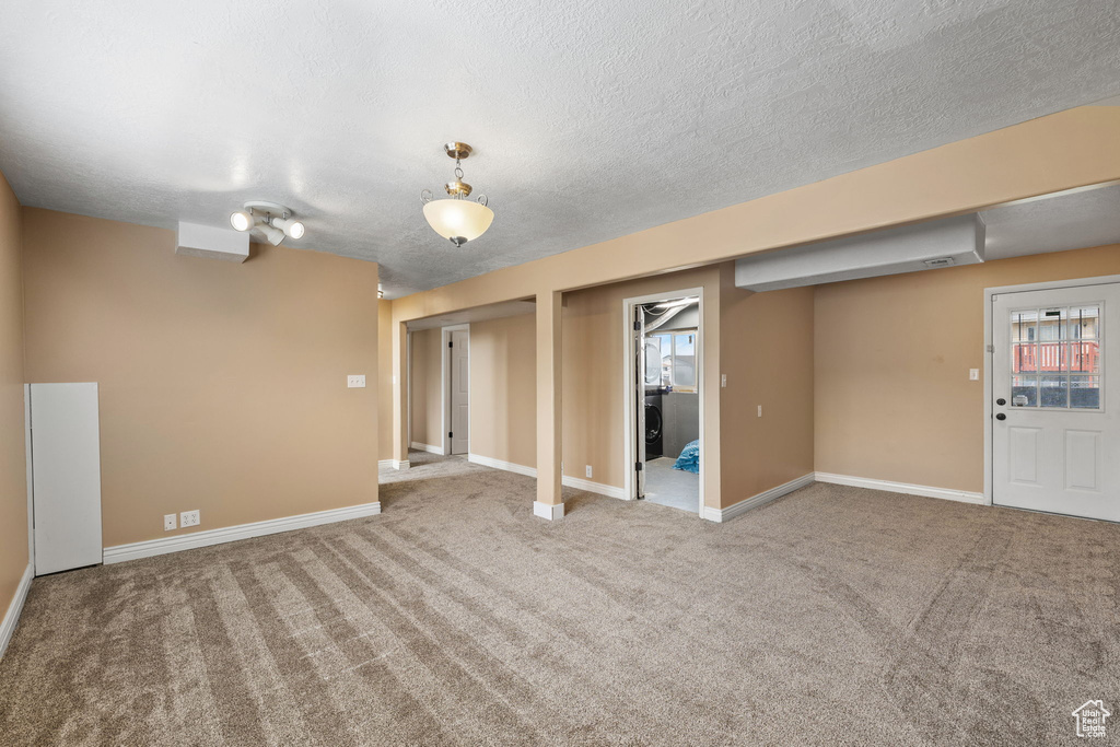 Basement featuring baseboards, carpet flooring, and a textured ceiling