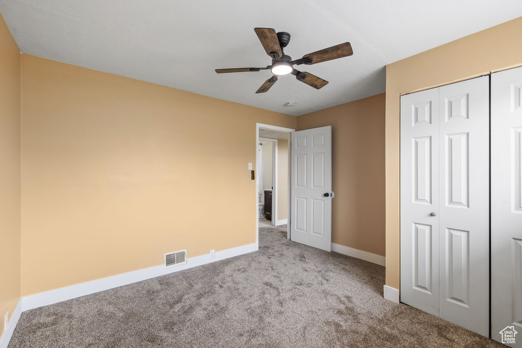 Unfurnished bedroom with a closet, visible vents, carpet, baseboards, and ceiling fan