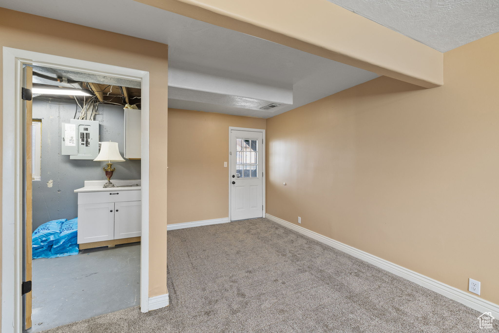 Below grade area with baseboards, carpet floors, visible vents, and electric panel