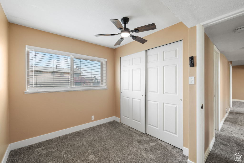 Unfurnished bedroom with a closet, carpet flooring, baseboards, and a ceiling fan