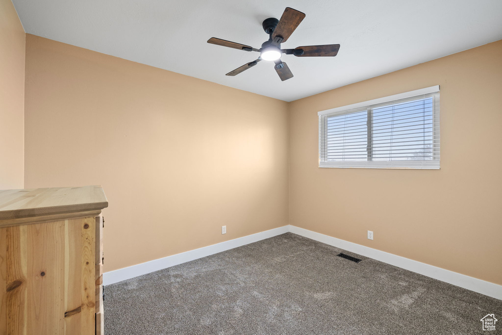 Carpeted spare room featuring baseboards, visible vents, and a ceiling fan
