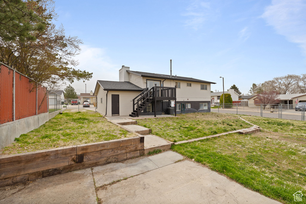 Back of house featuring a yard, stairway, fence, and a chimney
