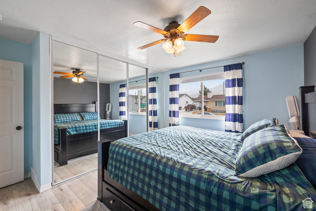 Bedroom with a closet, wood finished floors, and a ceiling fan