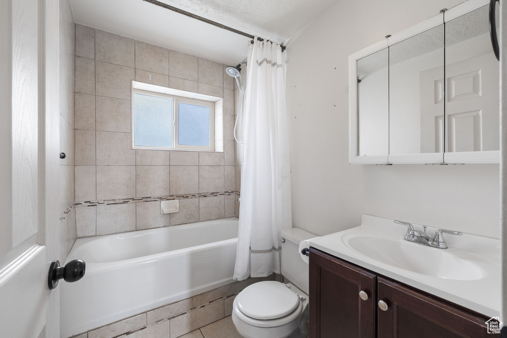 Full bath featuring toilet, vanity, and shower / bath combo with shower curtain