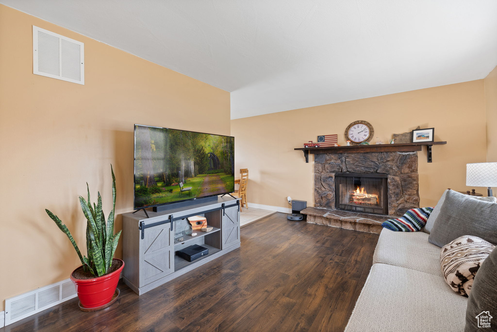 Living room featuring baseboards, a fireplace, visible vents, and wood finished floors