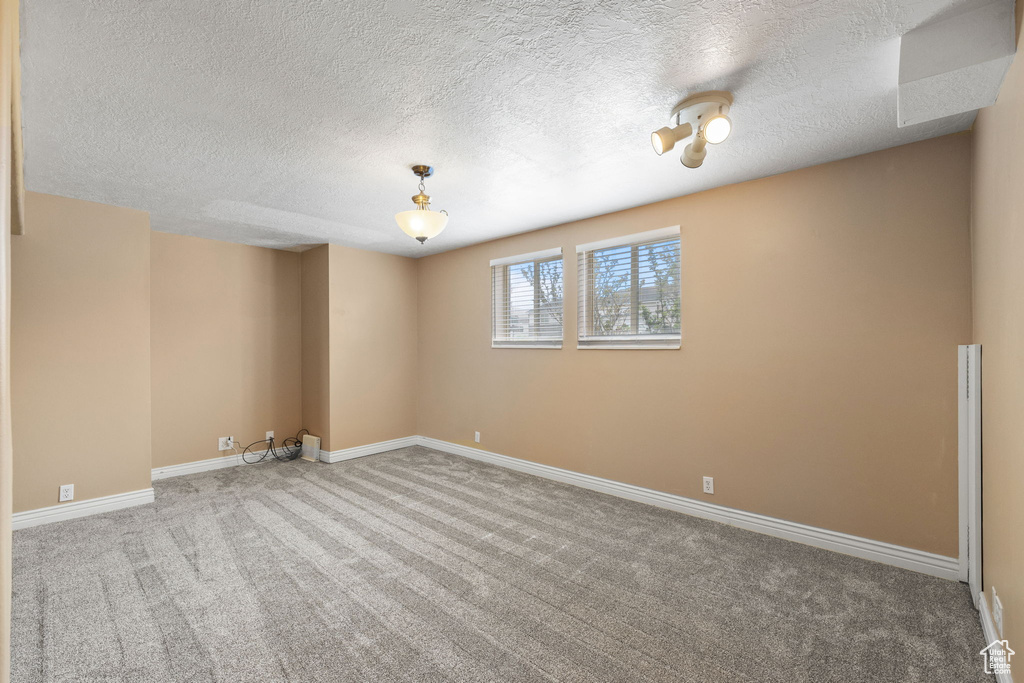Carpeted spare room with baseboards and a textured ceiling