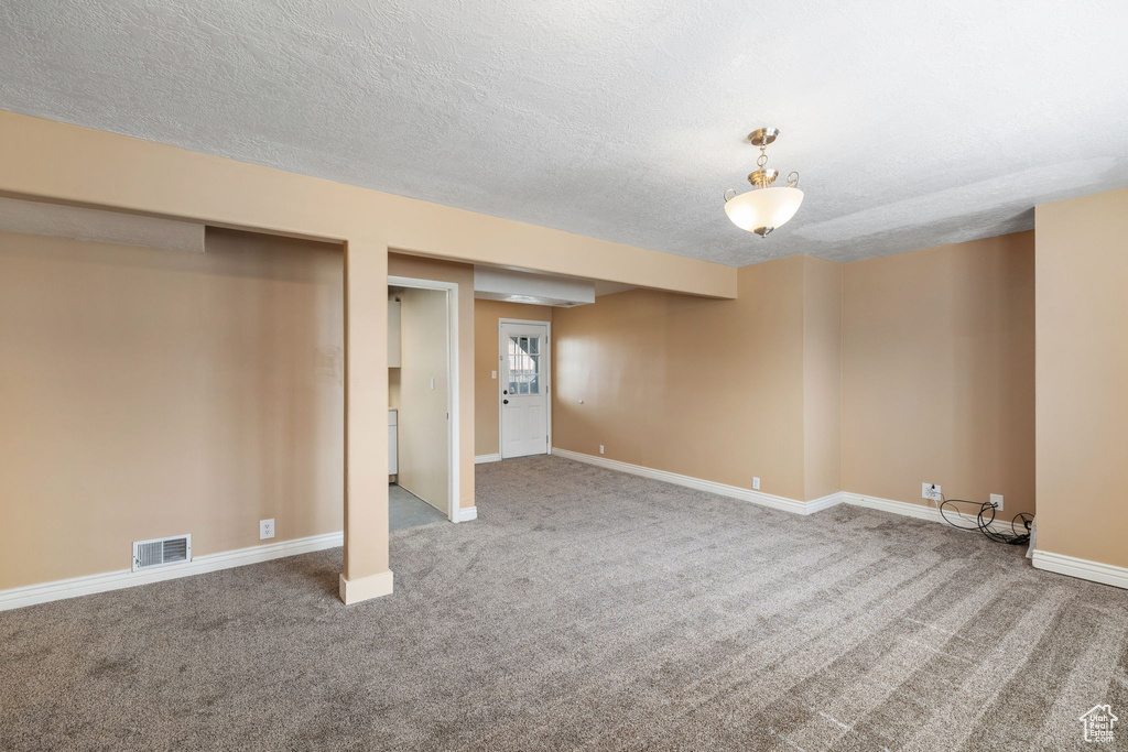 Basement featuring carpet, a textured ceiling, baseboards, and visible vents