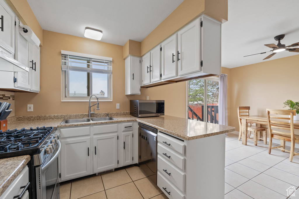 Kitchen with white cabinetry, a sink, light tile patterned flooring, ceiling fan, and appliances with stainless steel finishes