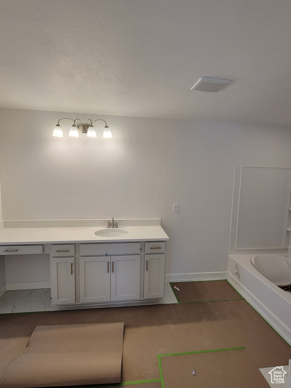 Bathroom with baseboards, a textured ceiling, visible vents, and vanity