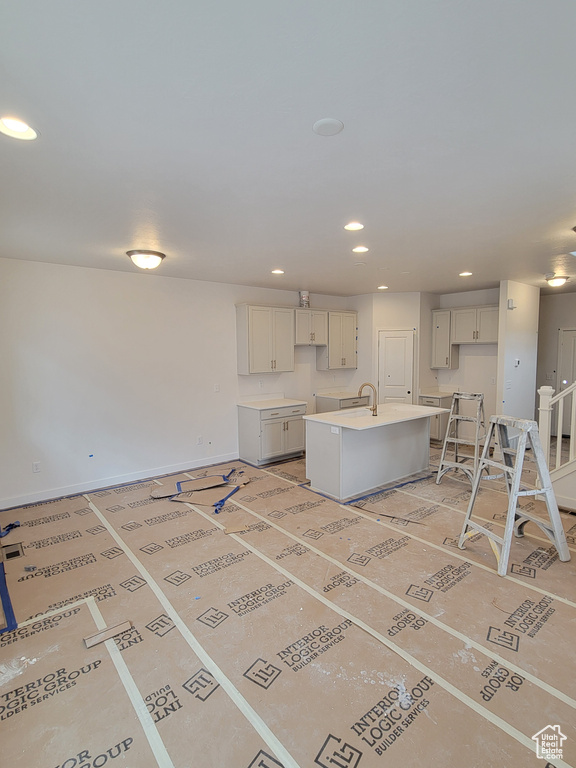 Kitchen with an island with sink, a sink, a breakfast bar, baseboards, and recessed lighting