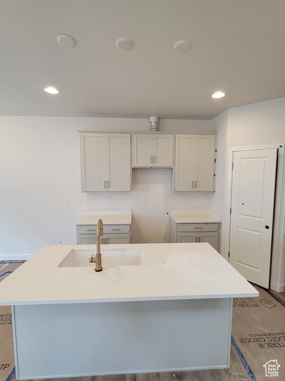 Kitchen featuring a kitchen island with sink, a sink, recessed lighting, and light countertops