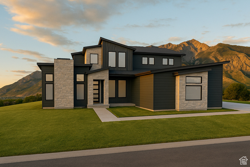 Contemporary house featuring stone siding, a front lawn, a mountain view, and board and batten siding