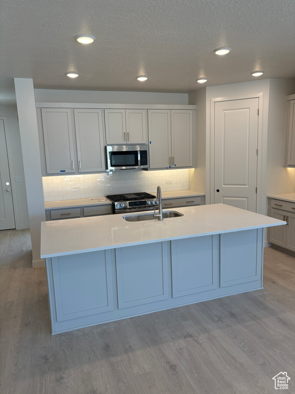 Kitchen featuring appliances with stainless steel finishes, light wood-style flooring, decorative backsplash, light countertops, and recessed lighting