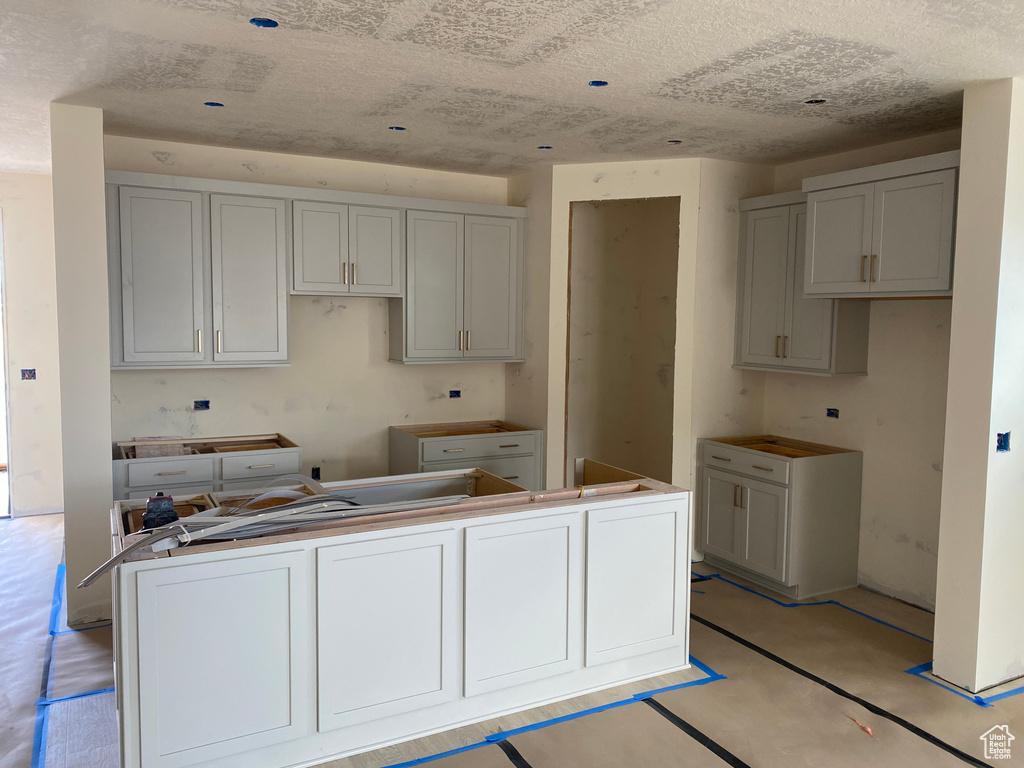 Kitchen with a kitchen island, a textured ceiling, and gray cabinets