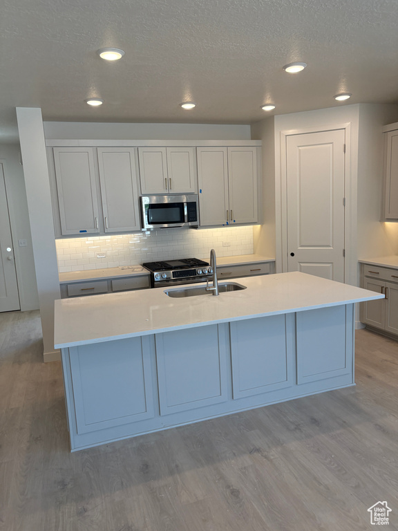 Kitchen featuring appliances with stainless steel finishes, light wood finished floors, backsplash, light countertops, and recessed lighting