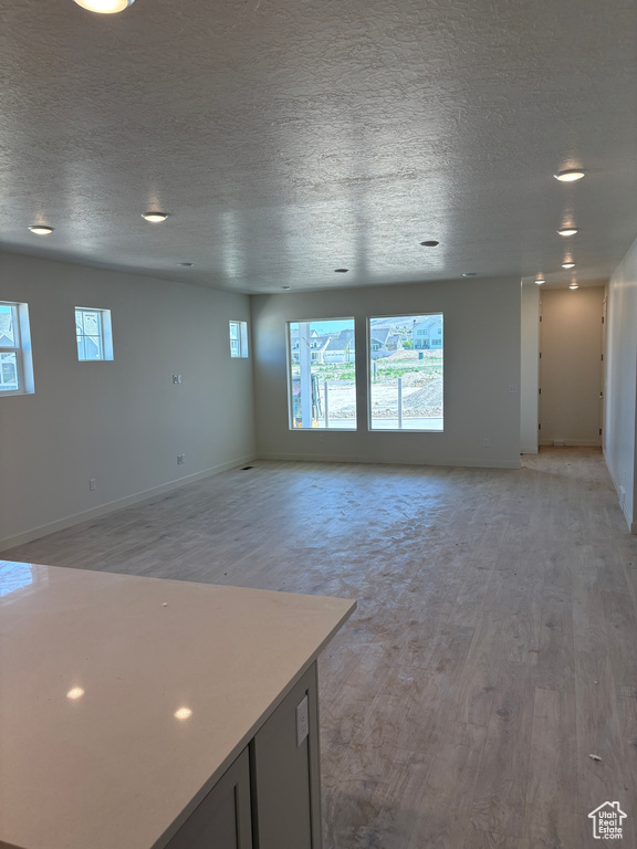 Spare room with light wood-style flooring, a textured ceiling, and recessed lighting